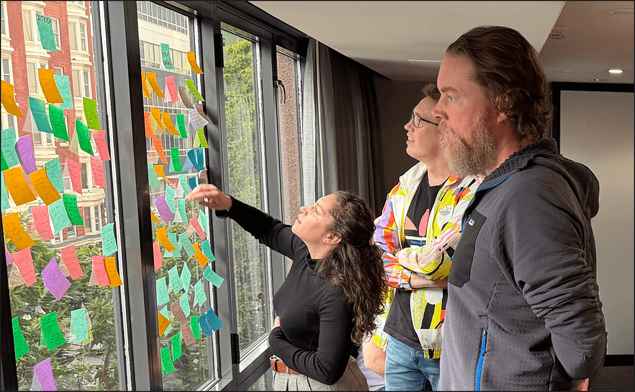 Observable team collaborating and reviewing research notes on a window covered with colorful sticky notes.